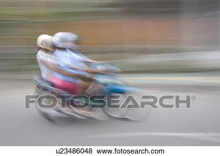 Stock Photo - Blurred image of people riding a motorbike in Bali. Fotosearch