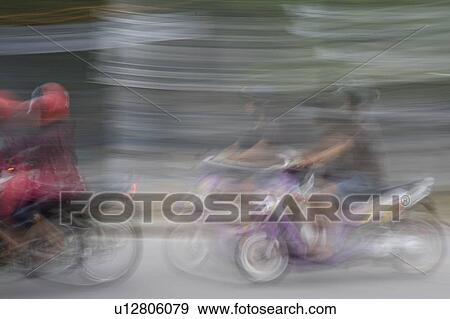 Stock Photo - Blurred picture of people riding on motorbikes in Bali. Fotosearch