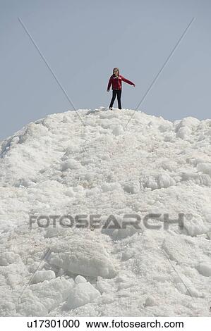 Stock Image - Girl standing on a pile of snow at Winnipeg Beach, Manitoba, Canada. Fotosearch