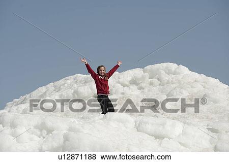 Stock Photo - Girl standing on a pile of snow at Winnipeg Beach, Manitoba, Canada. Fotosearch
