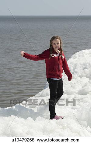 Stock Photo - Girl standing on a pile of snow at Winnipeg Beach, Manitoba, Canada. Fotosearch