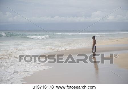 Stock Photo - Man standing on beach in Bali. Fotosearch