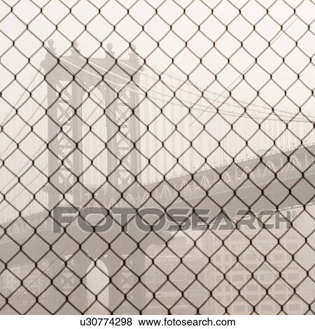 Stock Photo - Manhattan Bridge through a chain link fence in Manhattan, New York City, U. S. A.. Fotosearch