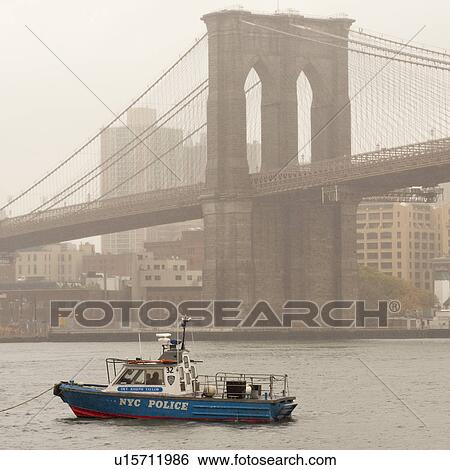 Stock Photograph - NYPD Boat on the East River with the Brooklyn Bridge in Manhattan, New York City, U. S. A.. Fotosearch