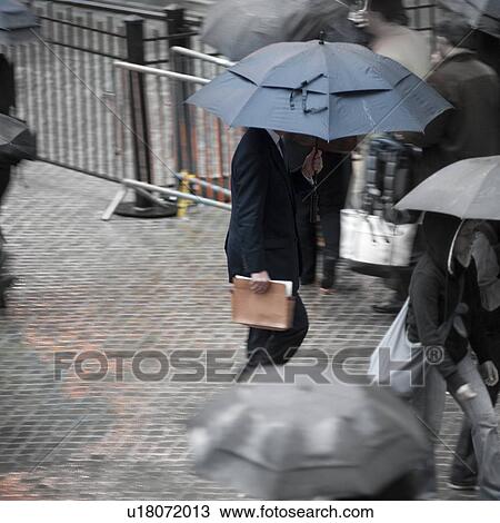 Stock Image - Overview of people walking with umbrellas in Manhattan, New York City, U. S. A.. Fotosearch