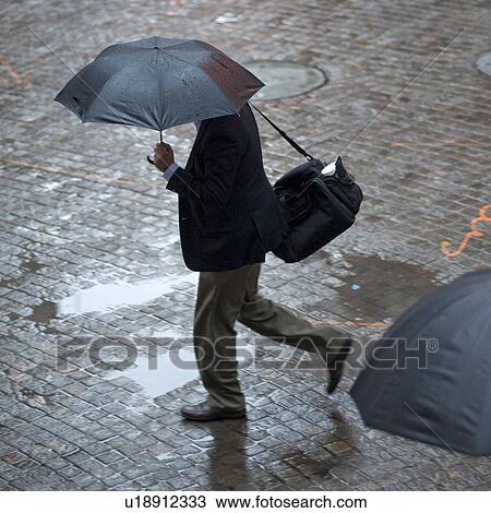 Stock Image - Overview of people walking with umbrellas in Manhattan, New York City, U. S. A.. Fotosearch