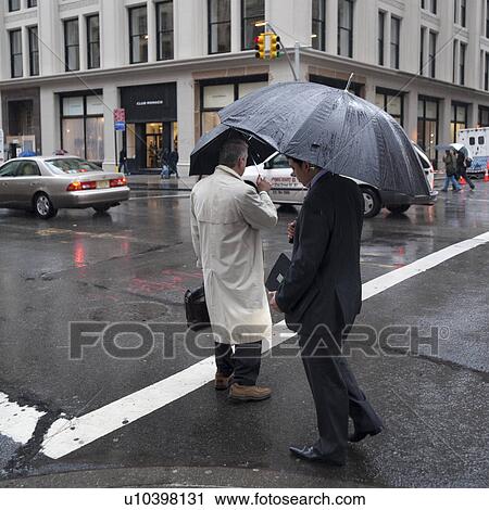 Stock Image - Pedestrians in the rain on the streets of Manhattan, New York City, U. S. A.. Fotosearch