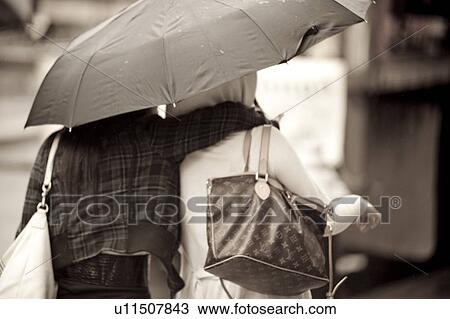 Stock Image - Pedestrians walking with umbrellas in Manhattan, New York City, U. S. A.. Fotosearch