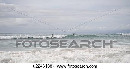 Stock Photo - People surfing in ocean along coast of Bali. Fotosearch