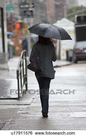 Stock Photograph - People walking with umbrellas on the streets of Manhattan, New York City, U. S. A.. Fotosearch