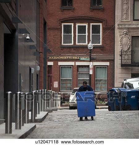 Stock Photo - Person pushing a container on a street in Boston, Massachusetts, USA. Fotosearch