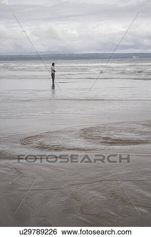 Stock Photograph - Person standing along shoreline in Bali. Fotosearch
