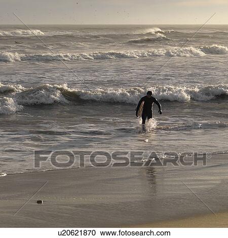 Stock Image - surfer along shoreline at The Hamptons, New York. Fotosearch