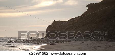 Stock Image - Surfer along the Hampton coastline. Fotosearch