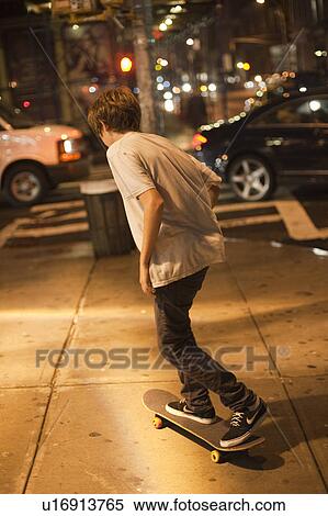 Stock Photography - Teenager riding a skateboard on sidewalk in Manhattan, New York City, U. S. A.. Fotosearch