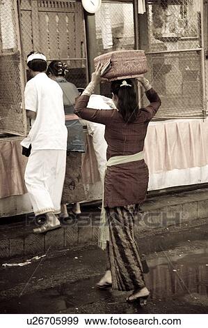 Stock Photo - Woman carrying a parcel on her head in Bali. Fotosearch