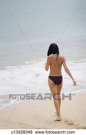 Woman walking along the beach in Bali View Large Photo Image Stock Photo - Woman walking along the beach in Bali. Fotosearch