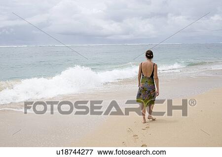 Stock Photo - Woman walking along the beach in Bali. Fotosearch