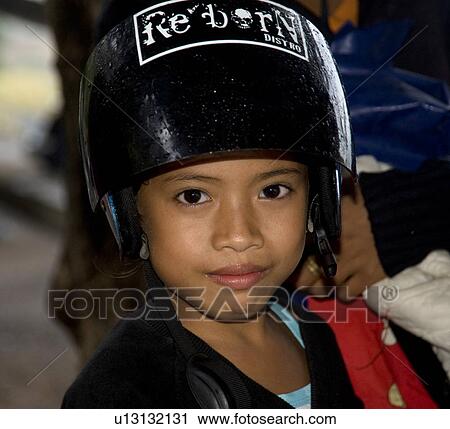 Stock Image - Young child wearing a helmet in Bali. Fotosearch