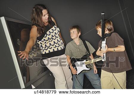 A Mother In Front Of The Television Screen Telling Her Boys To Stop Playing Their Music Game View Large Photo Image Stock Photo - A Mother In Front Of The Television Screen Telling Her Boys To Stop Playing Their Music Game. Fotosearch