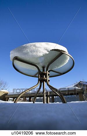 Stock Photograph - snow melting on a patio table; edmonton, alberta, canada. Fotosearch