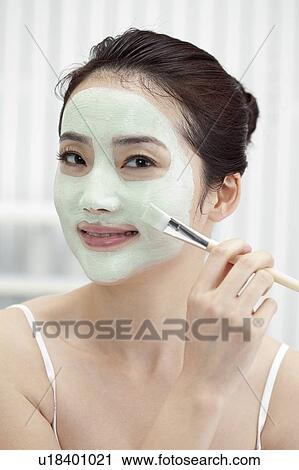 Stock Image - Beauty Treatment, Woman applying facial mask on face with a make-up brush. Fotosearch