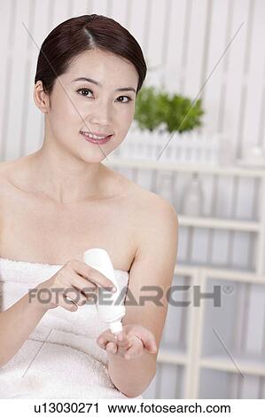 Stock Image - Beauty Treatment, Woman holding a bottle and smiling at the camera. Fotosearch