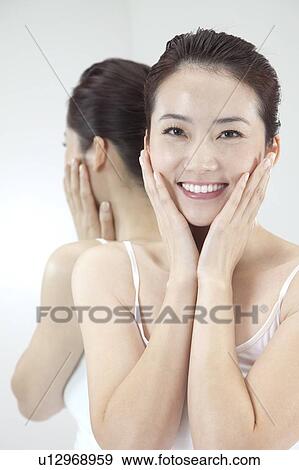 Stock Photo - Beauty Treatment, Woman smiling at the camera with hands on chin. Fotosearch