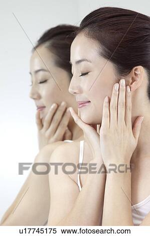 Beauty Treatment, Woman standing near the mirror with eyes closed and hands on chin View Large Photo Image Stock Photography - Beauty Treatment, Woman standing near the mirror with eyes closed and hands on chin. Fotosearch