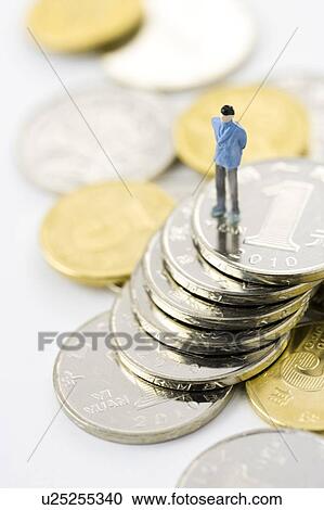Stock Image - Chinese Currency, A figurine man standing on a stack of coins. Fotosearch
