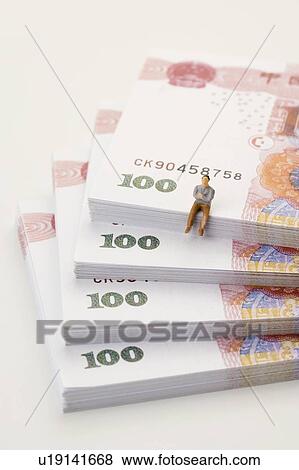 Stock Photo - Chinese Currency, a figurine man sitting on top of a stack of paper money. Fotosearch