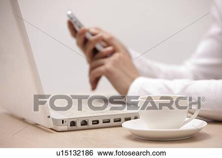 Stock Photograph - Close-up of a cup of tea and laptop on the table. Fotosearch