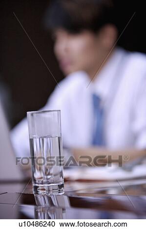 Stock Image - Close-up of a glass of water on conference table. Fotosearch