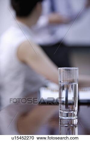 Stock Image - Close-up of a glass of water on conference table. Fotosearch