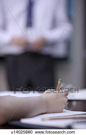 Stock Image - Close-up of hand holding a pencil and writing. Fotosearch