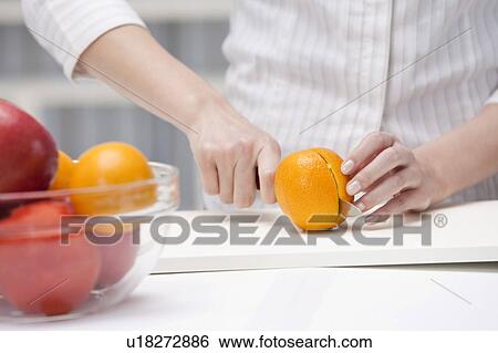 Close-up of hands cutting an orange View Large Photo Image Stock Photograph - Close-up of hands cutting an orange. Fotosearch