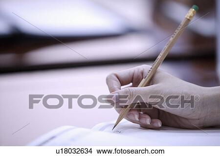 Picture - Close-up of human hand holding a pencil and writing. Fotosearch
