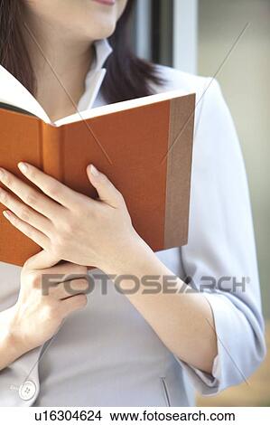 Close-up of woman holding a book View Large Photo Image Picture - Close-up of woman holding a book. Fotosearch