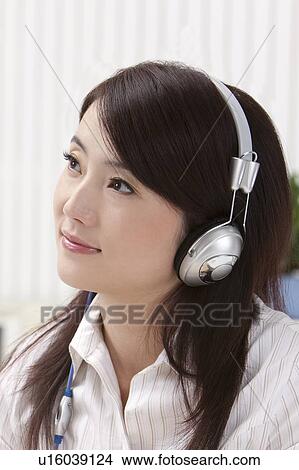 Picture - Close-up of woman listening music and looking away with smile. Fotosearch