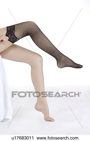 Stock Image - Close-up of young woman getting dressed on one leg with sexy stocking. Fotosearch