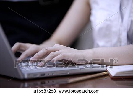 Stock Image - Close-up of young woman's hands using laptop. Fotosearch