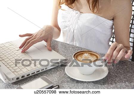Stock Photo - Coffee Break, People using laptop and holding a cup of cappuccino. Fotosearch
