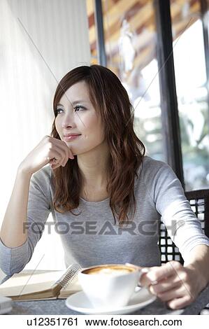 Stock Image - Coffee Break, Taste of Life, Young woman holding a cup of coffee and looking away with smile. Fotosearch