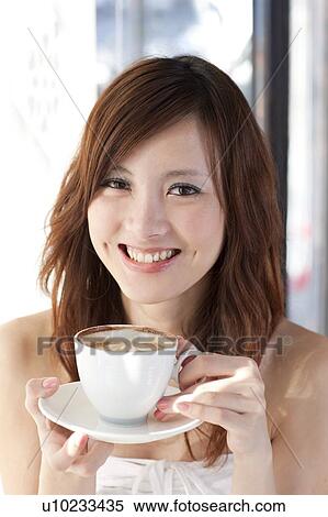 Stock Photography - Coffee Break, Taste of Life, Young woman holding a cup of coffee and looking at the camera with smile. Fotosearch