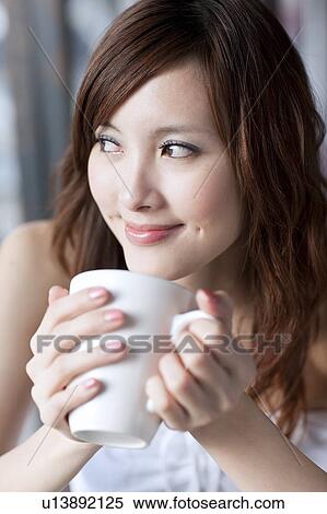 Stock Photography - Coffee Break, Young woman holding a cup and looking away with smile. Fotosearch