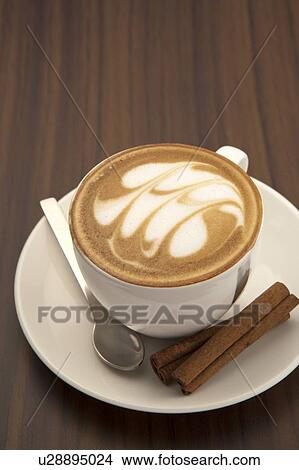 Picture - Coffee, Cappuccino, Close-up of a cup of cappuccino with pattern and dessert on the saucer. Fotosearch