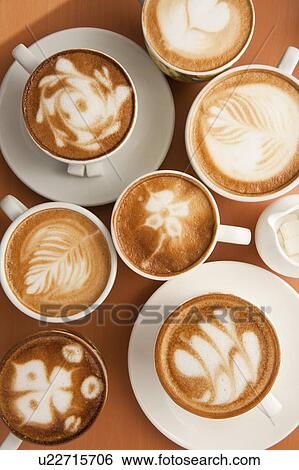 Stock Photograph - Coffee, Cappuccino, Close-up of cups of cappuccino with different pattern on the table. Fotosearch
