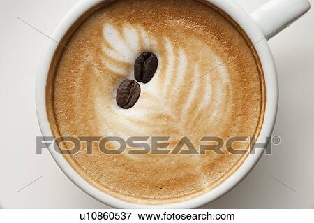 Stock Photo - Coffee, Close-up of two coffee beans on a cup of cappuccino. Fotosearch