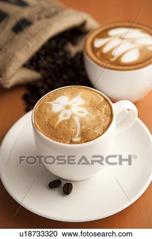 Stock Image - Coffee, Coffee Culture, Close-up of two cups of cappuccino with pattern on the table. Fotosearch