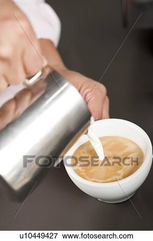 Coffee, Human hands pouring milk into a cup of coffee View Large Photo Image Stock Photo - Coffee, Human hands pouring milk into a cup of coffee. Fotosearch